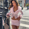 Woman in a pink outfit standing on a city street corner.