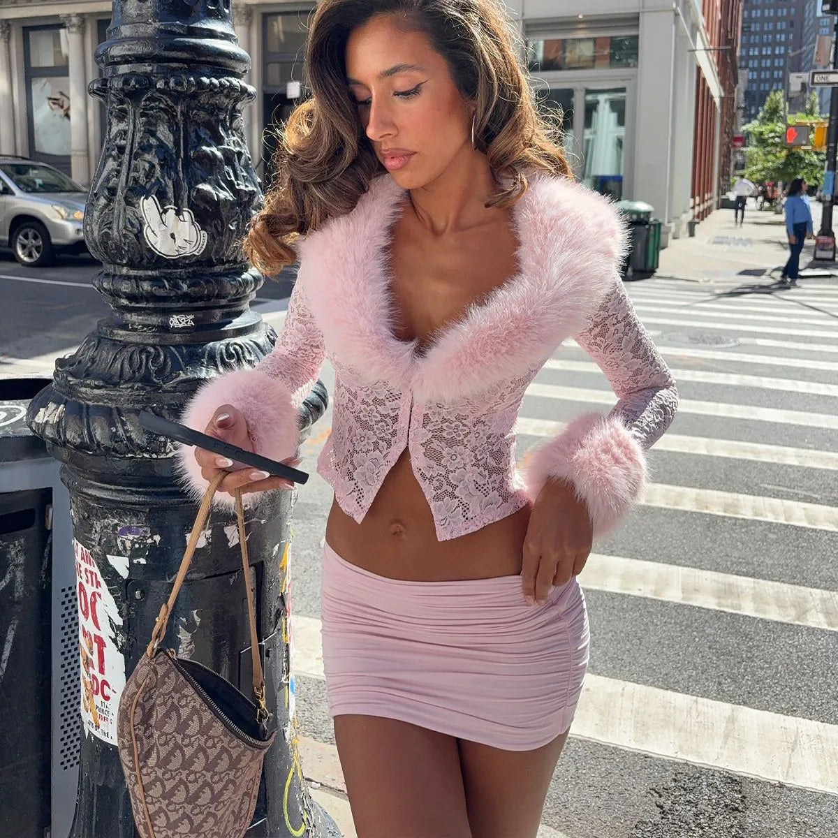 Woman in a pink outfit standing on a city street corner.