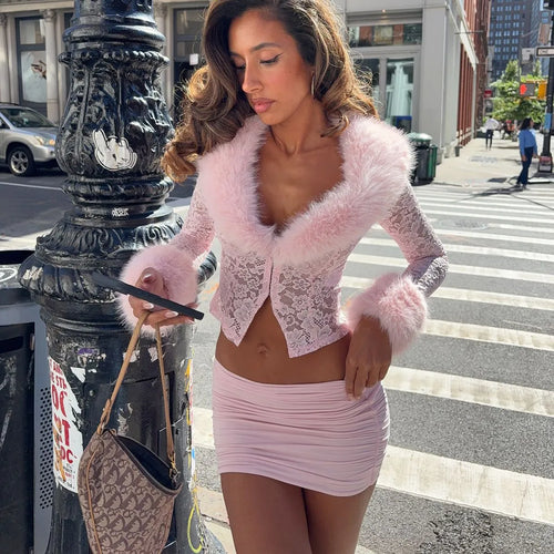 Woman in a pink outfit standing on a city street corner.